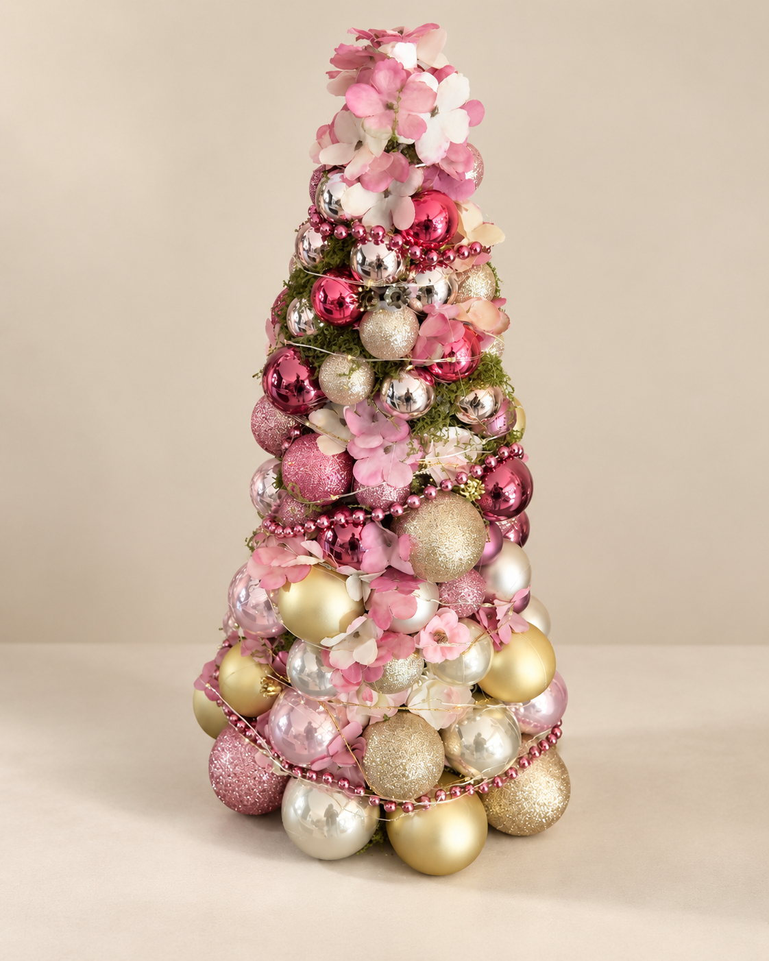 Grote decoratieve kerstboom met roze bloemen en roze, gouden en zilveren kerstballen